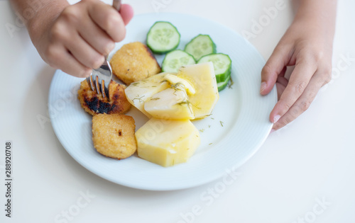 boy eating simple and cheap food for children - nuggets, cucumbers and potatoes