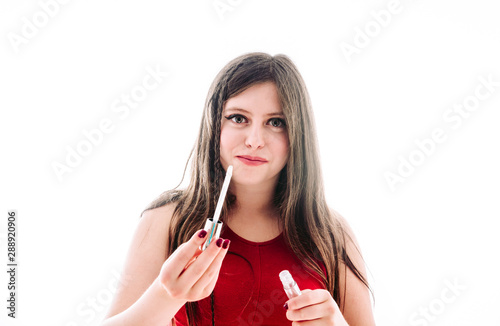 Teenage girl applying lip gloss to look prettier.