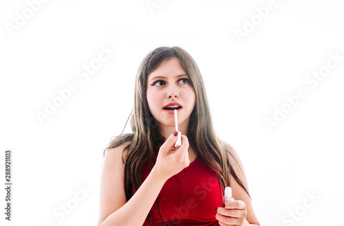 Teenage girl applying lip gloss to look prettier.