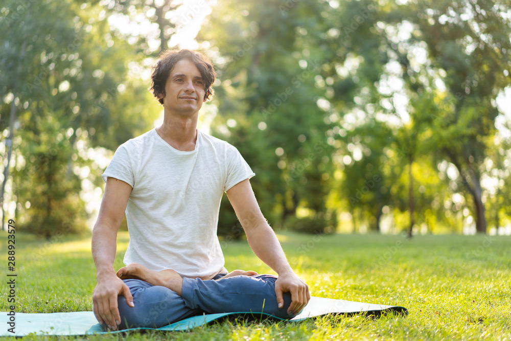 Fototapeta premium Young man meditating outdoors in the park