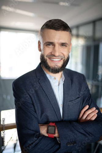 Bearded businessman smiling broadly while feeling good
