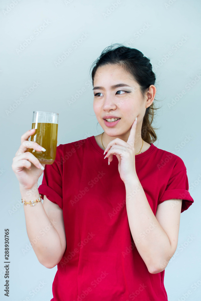 Woman touching her face skin while holding a glass of green tea Woman touching her face skin while holding a glass of green tea
