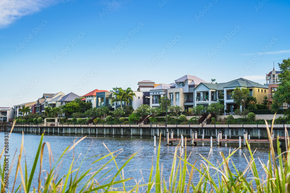 Wide panoramic view of Emerald Lakes residences across the lake, on a blue sky background during a beautiful sunset. Gold Coast, Australia. Wide panoramic view of Emerald Lakes residences across the lake, on a blue sky background during a beautiful sunset. Gold Coast, Australia.