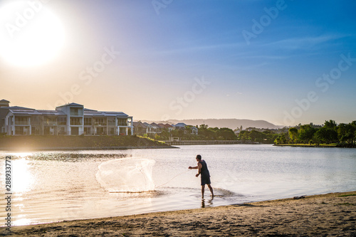 A man is fishing in the river at Emerald Lakes during a stunning sunset. 