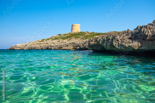 View on the beach Calo Roig with crystal water and the Defense Tower Alcaufar on Menorca. photo