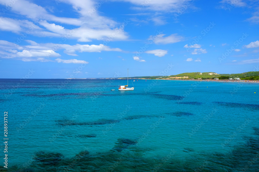 Obraz premium View on the beach Son Bou and white boat on the Balearic Island Menorca, Spain.