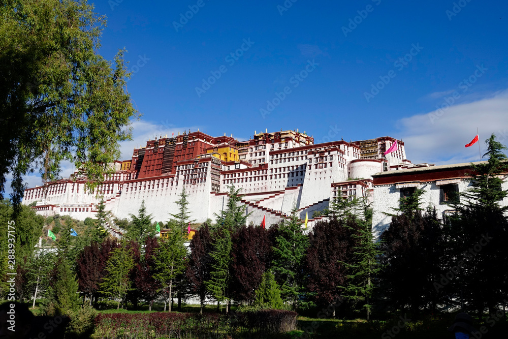 Scenic view of ancient Potala Palace atop a Tibetan mountain and a lovely park.