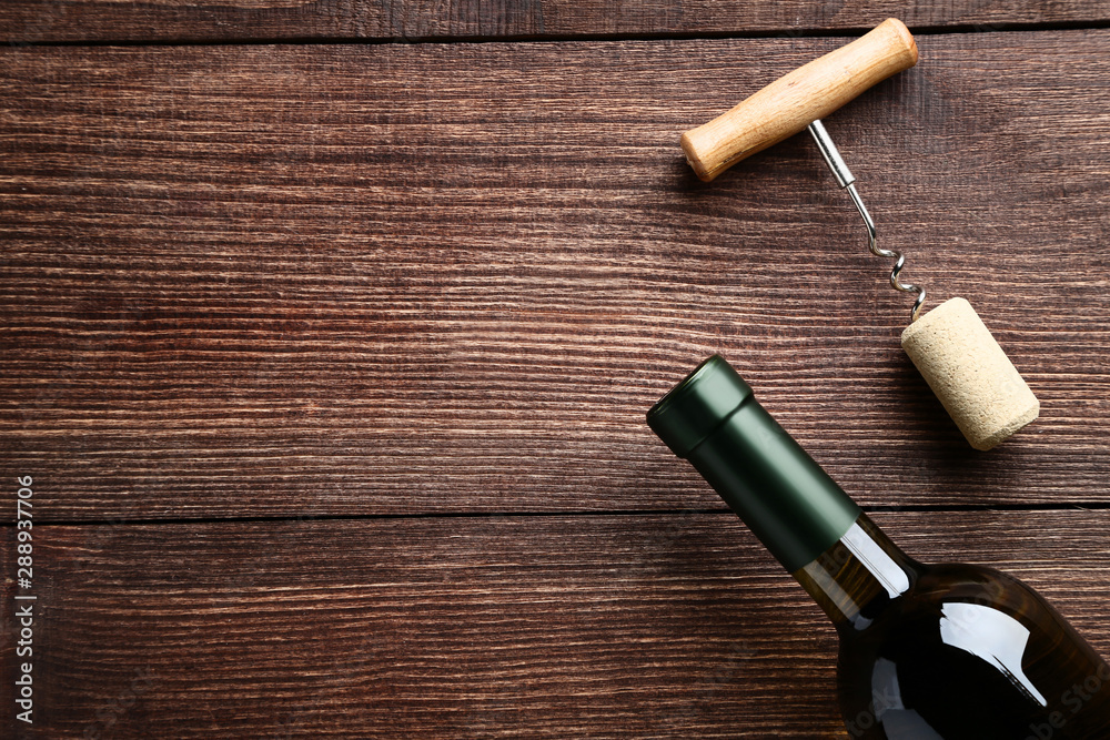 Wine bottle with cork and corkscrew on brown wooden table