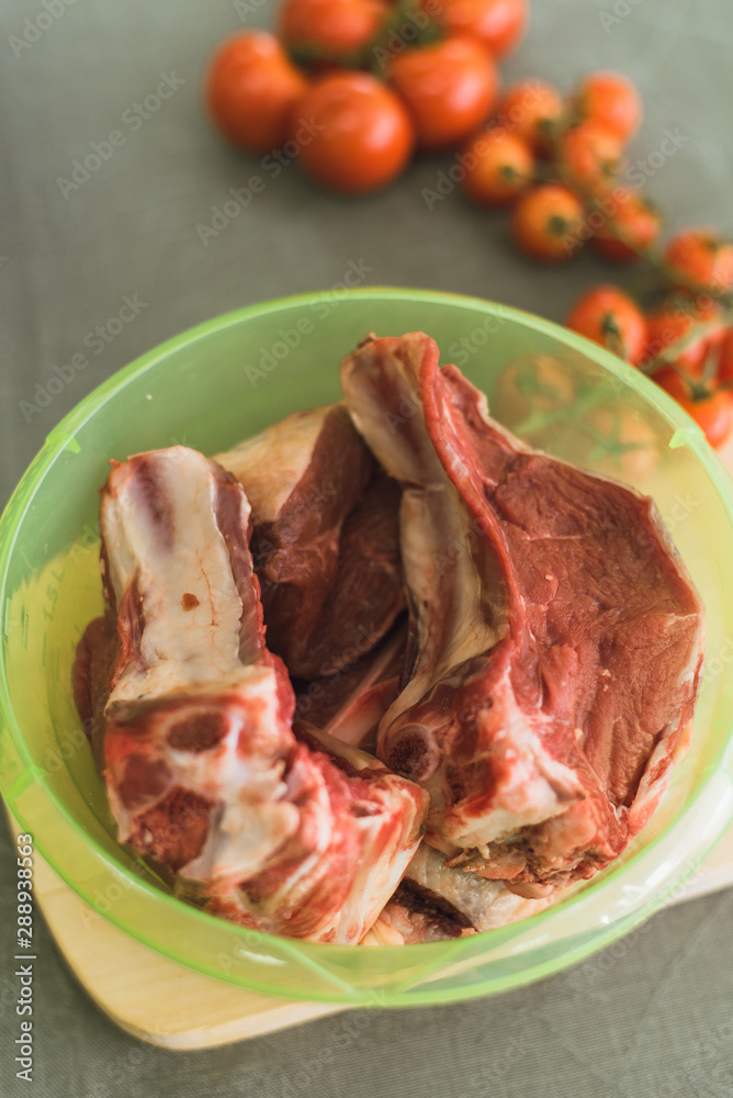 meat on the bone in a plastic vessel. fresh meat for cooking. meat on the bone in a plastic vessel. fresh meat for cooking.