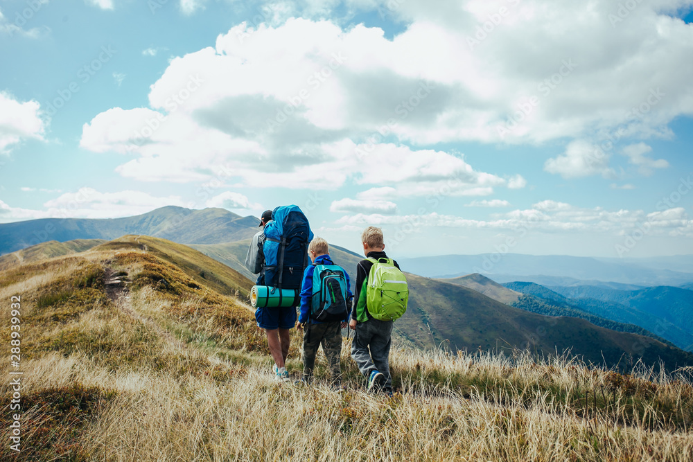 Fototapeta premium Family, dad and children go camping in the mountains