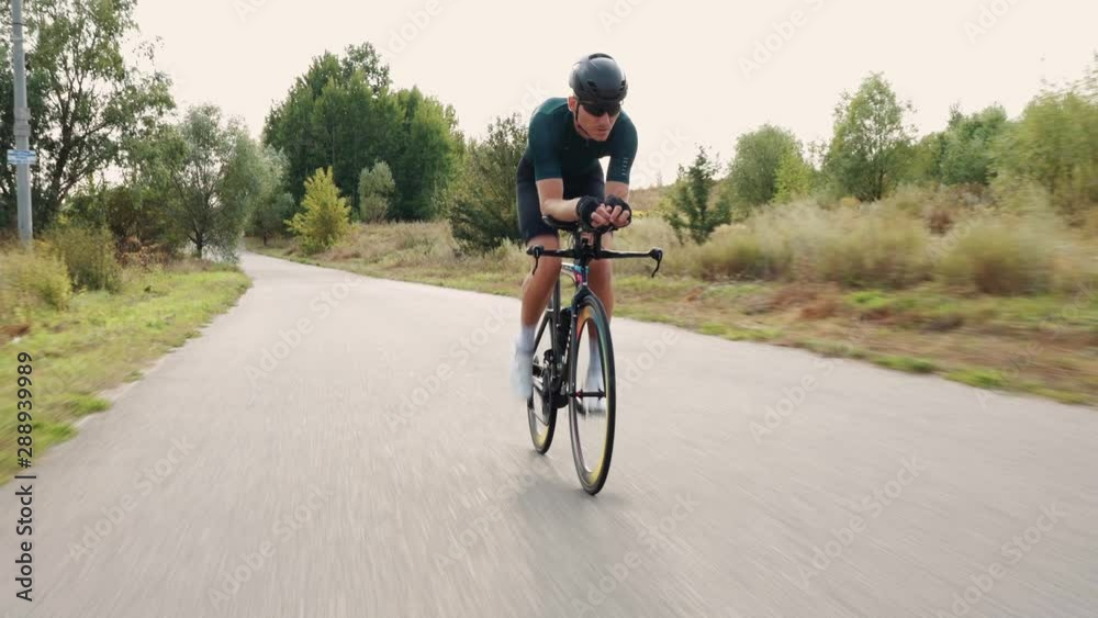 A professional cyclist in a helmet and sports equipment rides on a highway at sunset A professional cyclist in a helmet and sports equipment rides on a highway at sunset