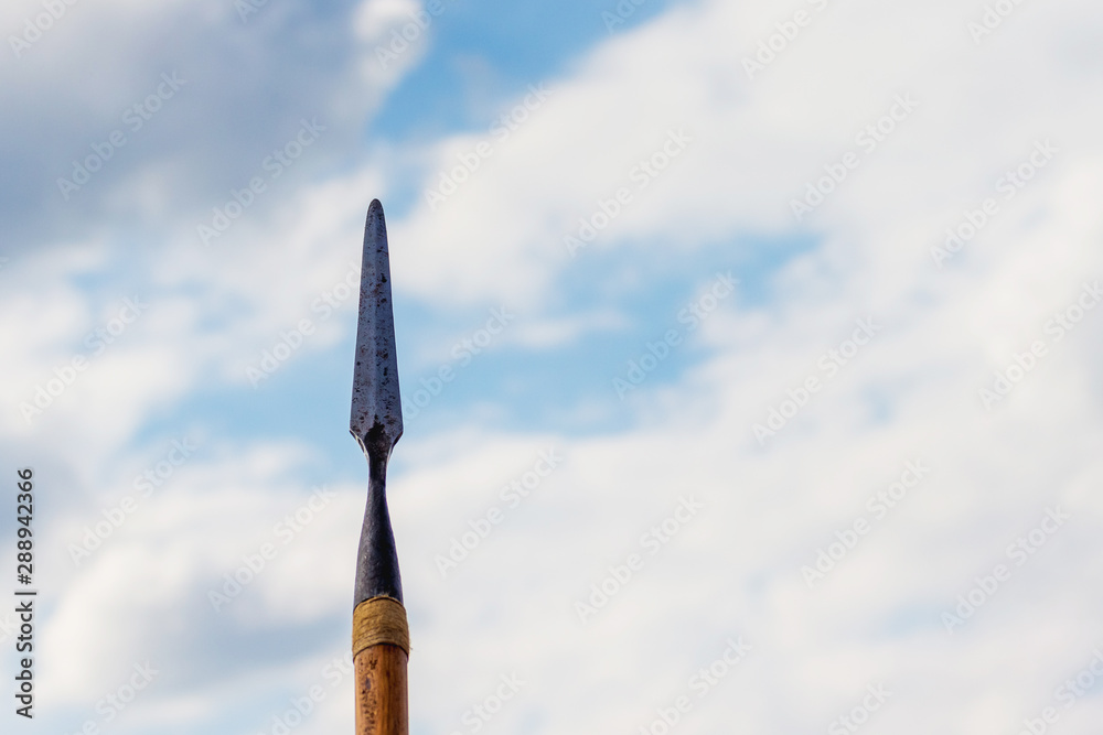Naklejka premium Spear on sky background. Cold weapons. A symbol of war and protection_
