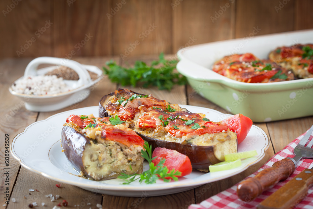 Baked eggplant or aubergine stuffed with minced meat and vegetables. Turkish or Greek homemade cuisine. Eggplant dish on wooden background. Baked eggplant or aubergine stuffed with minced meat and vegetables. Turkish or Greek homemade cuisine. Eggplant dish on wooden background.