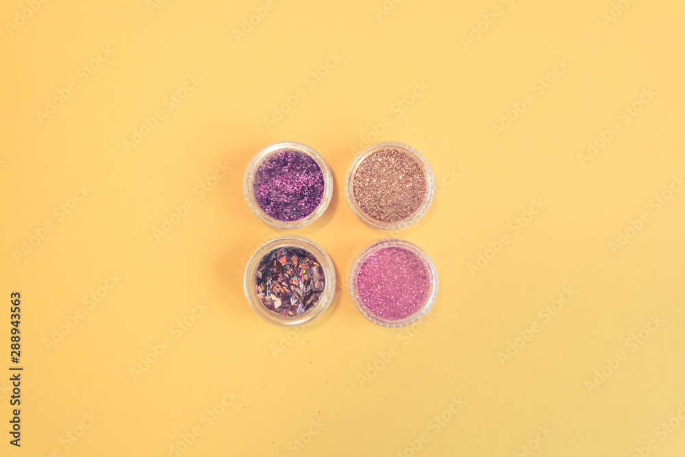 Top view of manicure and pedicure equipment on yellow background. Beauty, care and fashion concept. Professional tools for manicure. Purple, Pink and Gold Nail Glitter. Copy space Top view of manicure and pedicure equipment on yellow background. Beauty, care and fashion concept. Professional tools for manicure. Purple, Pink and Gold Nail Glitter. Copy space