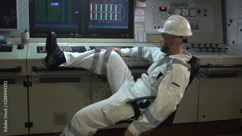 bored engineer sitting in a chair with his foot on the control panel