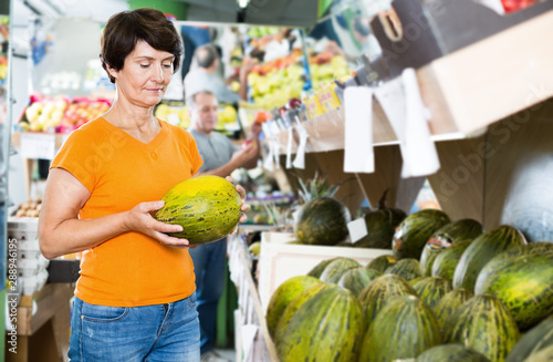 Female is choosing green melon in the supermarket