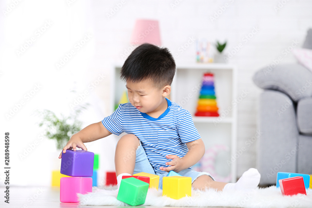 Beautiful boy sitting and playing with plastic toys at home Beautiful boy sitting and playing with plastic toys at home