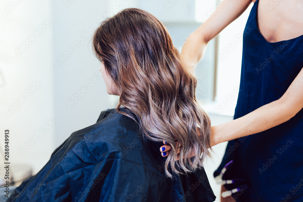 Fototapeta premium Beautiful hairstyle of young woman after dying hair and making highlights in hair salon.