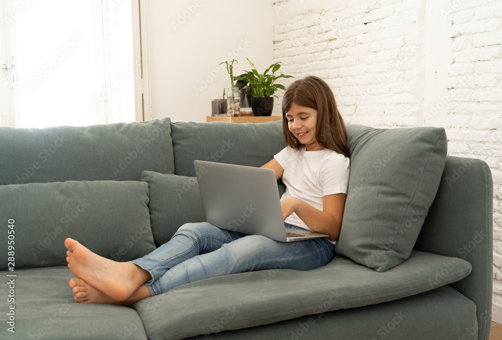 Beautiful cute charming young girl playing and surfing the internet on laptop at home Beautiful cute charming young girl playing and surfing the internet on laptop at home