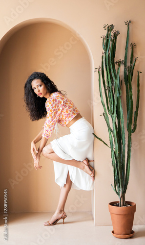 Thoughtful cute woman in flowery blouse and white skirt posing in an arc photo