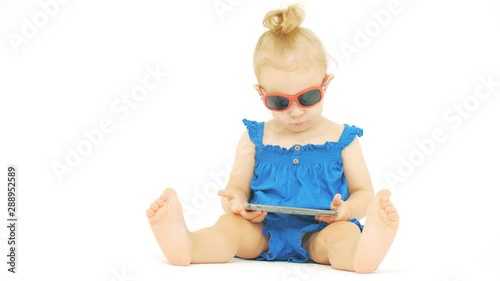 Serious baby wearing sunglasses looks at the smartphone photo