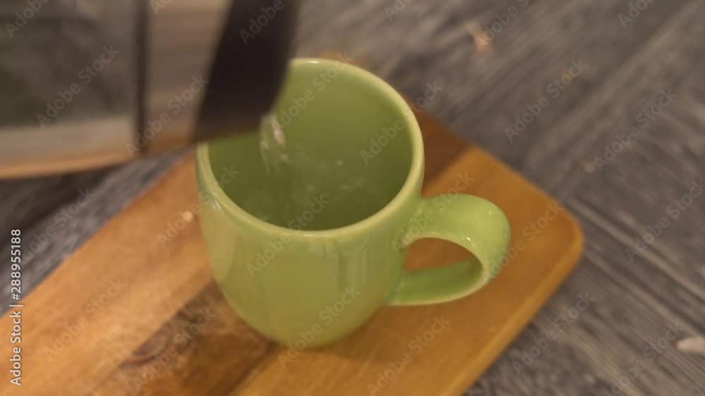 hot water is poured into a tasser with a black tea bag
