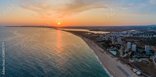 Aerial sunset view of Praia dos Tres Irmaos (Three Brothers beach) in Alvor, famous tourist destination in Western Algarve Coast, Portugal.