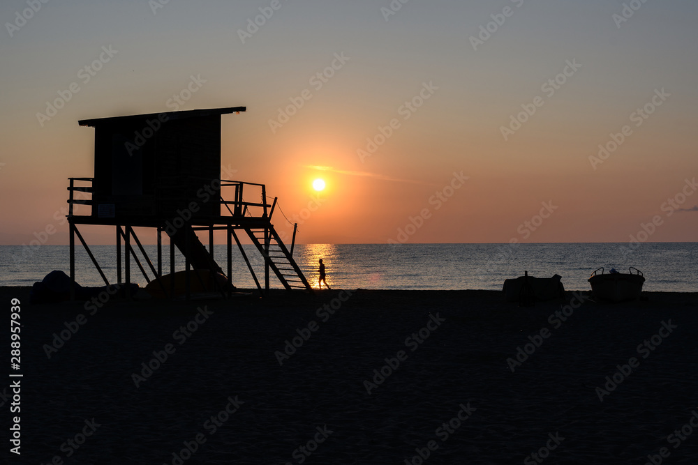 silhouette of a Lifeguard tower and a runner in Greece at sunrise 