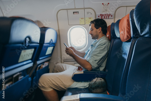 Fotografie The guy is flying in an airplane with a phone in hand