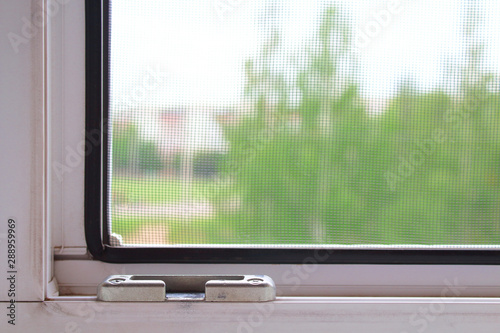 Double-glazed window and mosquito net. Close-up. View from the apartment to the street. Background. Texture.