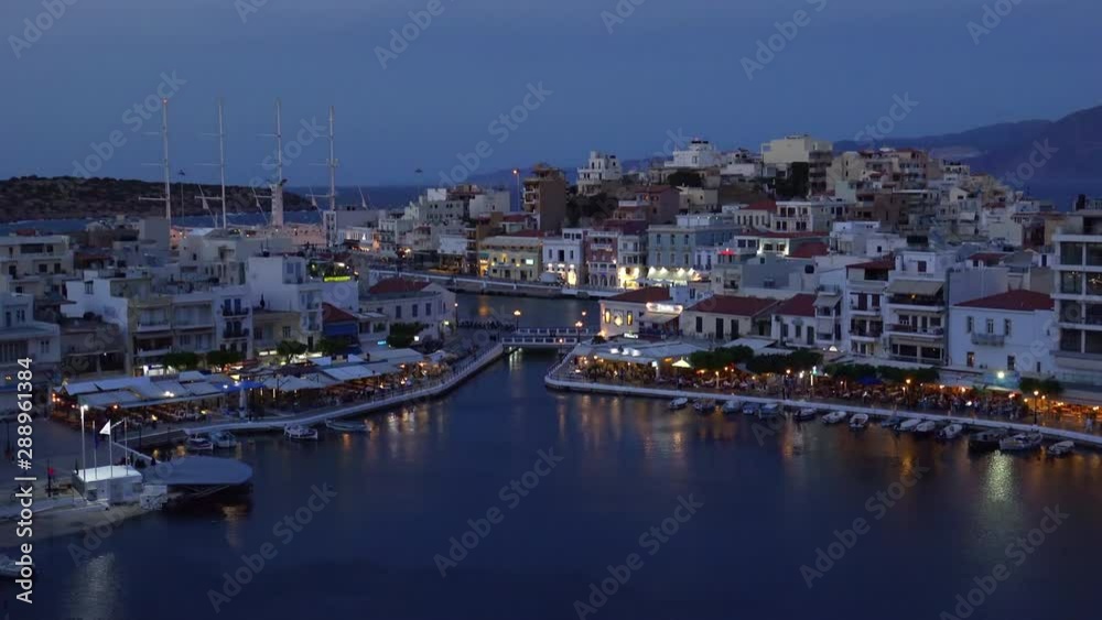 Beautiful sunset at Agios Nikolaos city, Port at Aegean sea. Crete,Greece. Peaceful harbor of Voulismeni Lake. Long promenade with restaurants. Panoramic view of seaport with yachts and boats at quay Beautiful sunset at Agios Nikolaos city, Port at Aegean sea. Crete,Greece. Peaceful harbor of Voulismeni Lake. Long promenade with restaurants. Panoramic view of seaport with yachts and boats at quay