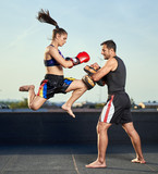 Young woman kickboxer in urban environment, training