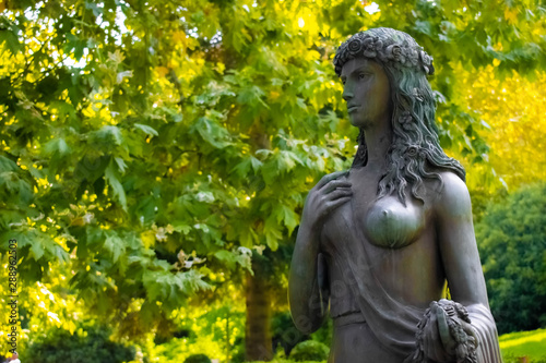 The statue of Flora in Paradise Park on a background of green leaves © Николай Смирнов