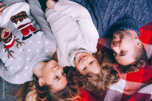 A happy family. Mom, dad and son dressed in sweaters are lying on the floor. Close-up portraits of happy parents and children.