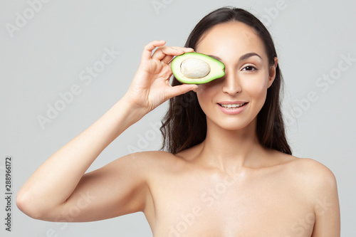 Young beautiful woman holding avocado