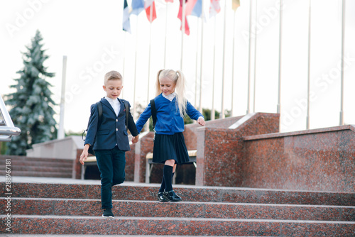 Little students go to school. Schoolchildren on background of flags of foreign countries.