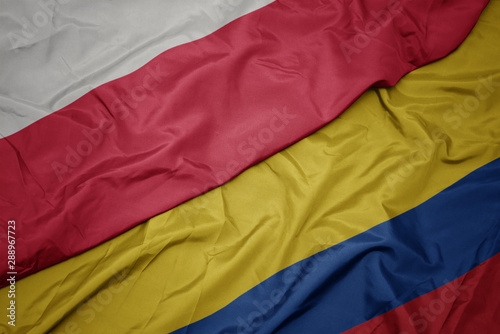 waving colorful flag of colombia and national flag of poland.