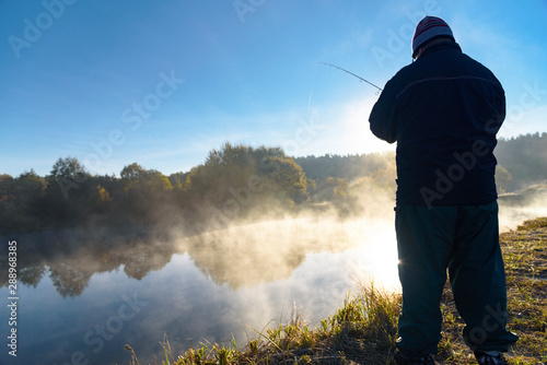 man catches fish on the river Snov in autumn, October 2018. Ukraine, the city of Chernigov photo