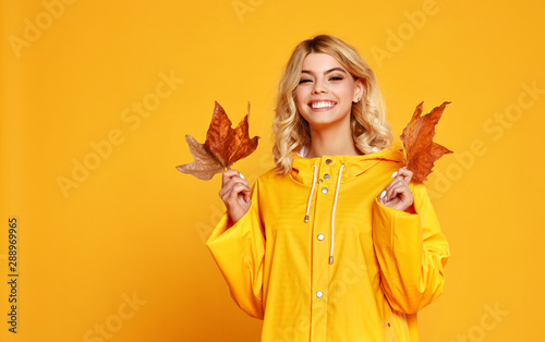 happy emotional girl with autumn leaves on colored yellow background