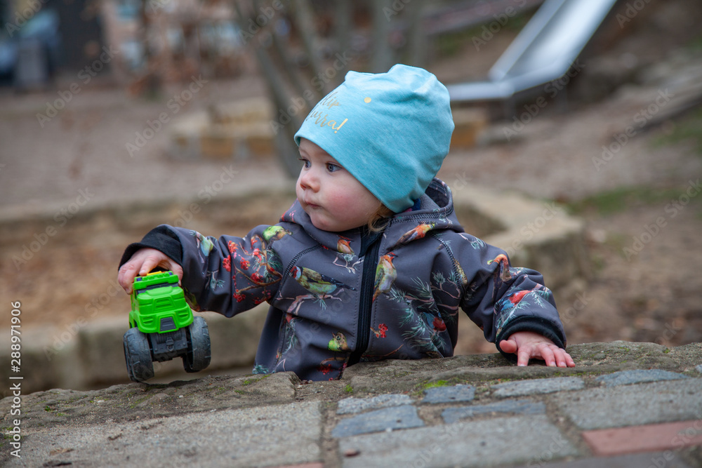 Kind Hannah beim unbeschwerten Spielen in einem Sandkasten. Das Kindergartenmädchen ist je nach Stimmung aufgeweckt, frech, froehlich, energievoll, eben ein richtig suesses Girly.