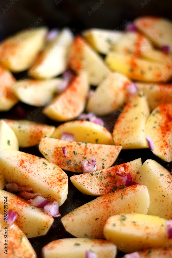 Cut potatoes seasoned with purple onion, basil and smoked paprika. Selective focus. Cut potatoes seasoned with purple onion, basil and smoked paprika. Selective focus.