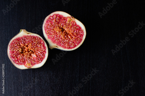 Half ripe fig isolated on dark wooden background. Top view. photo