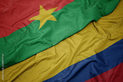 waving colorful flag of colombia and national flag of burkina faso.