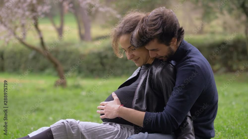love,tenderness,expectation. happy couple waiting for a baby sitting on grass love,tenderness,expectation. happy couple waiting for a baby sitting on grass