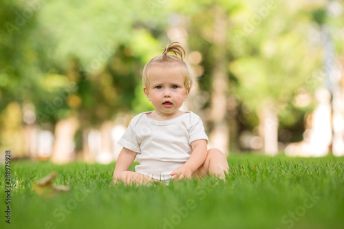 baby girl in a white sandpit on the green grass playing pyramid