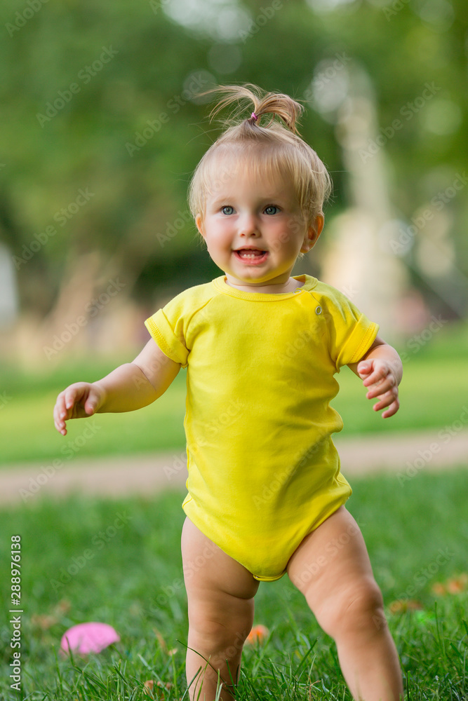 baby girl in white bodysuit on the green grass playing pyramid baby girl in white bodysuit on the green grass playing pyramid