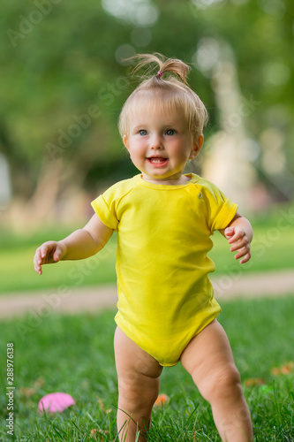 baby girl in white bodysuit on the green grass playing pyramid