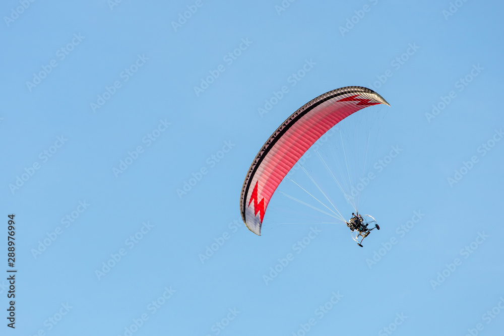 bright paraglider with a motor flies in the blue sky bright paraglider with a motor flies in the blue sky