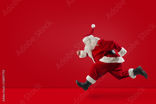 Santa Claus runs fast on red background photo