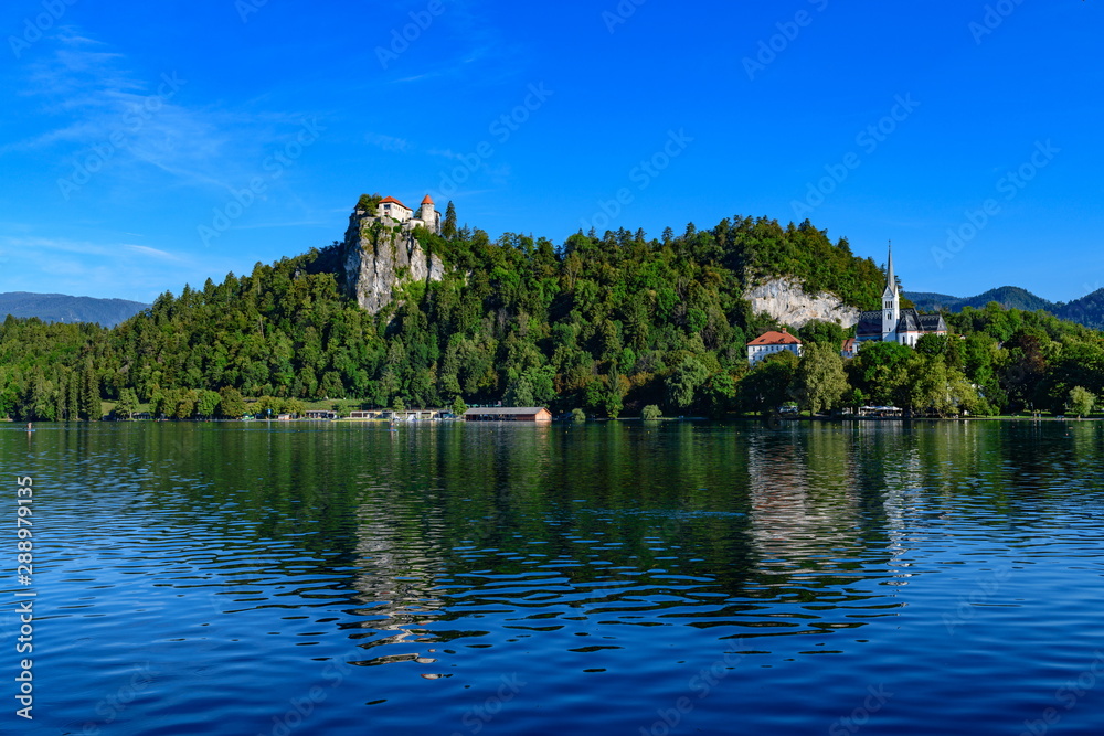 Beautiful view of the shore of Lake Bled with a medieval castle and the Catholic Church of St. Martin.